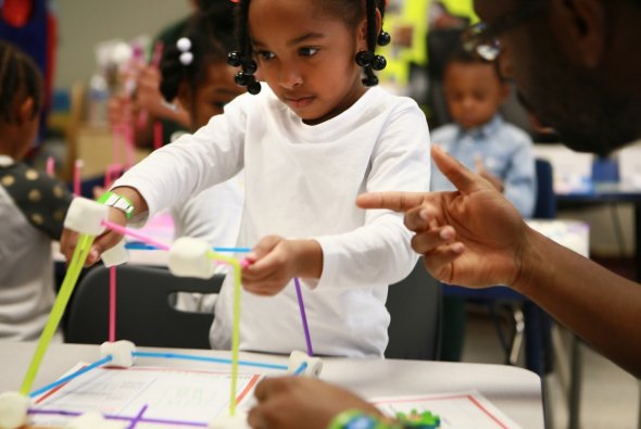 Kindergarten student building with marshmallows and straws