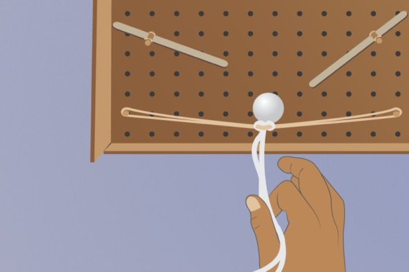 Rubber bands on stretched out on a  peg board with ball pulled back ready to launch