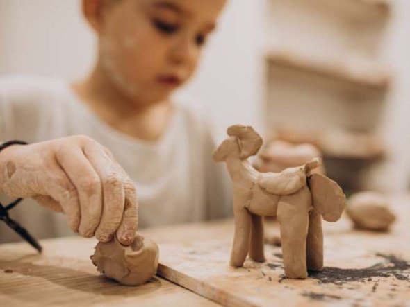 Kindergarten student making a clay horse