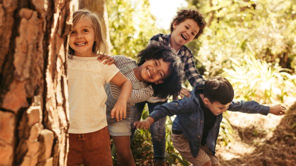 Four kindergarten students play in the woods