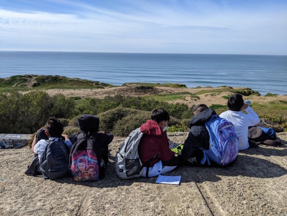Students watching the ocean on a ledge