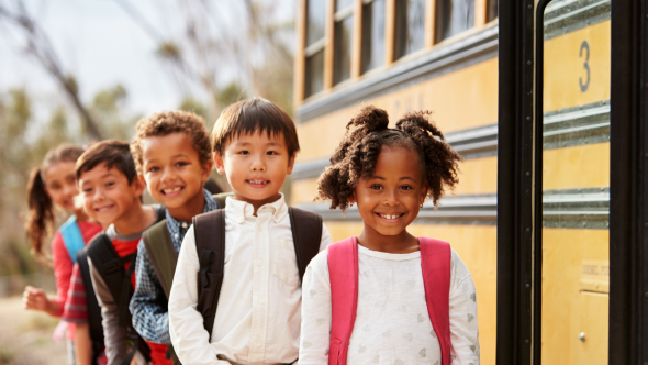 Child smiling near school bus