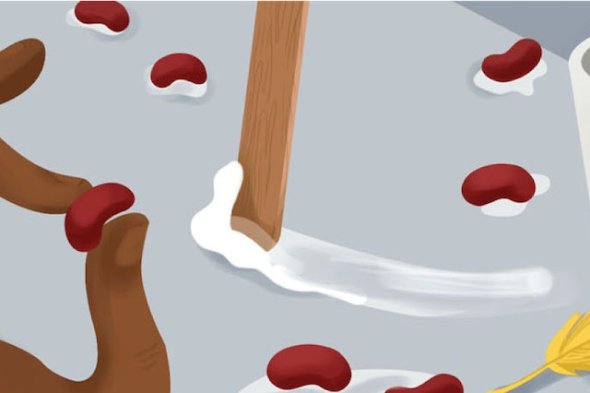 A hand holding a bean and, in the background, more beans in a grey substance