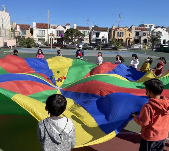 Students in a circle holding the edges of a parachute