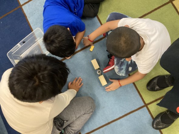 Three students collaboratively balancing objects