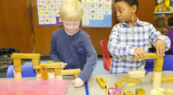 two first-grade students constructing with wooden blocks