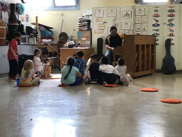group of students seated before a piano in music class