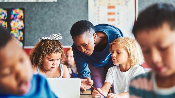 teacher helping young children with technology