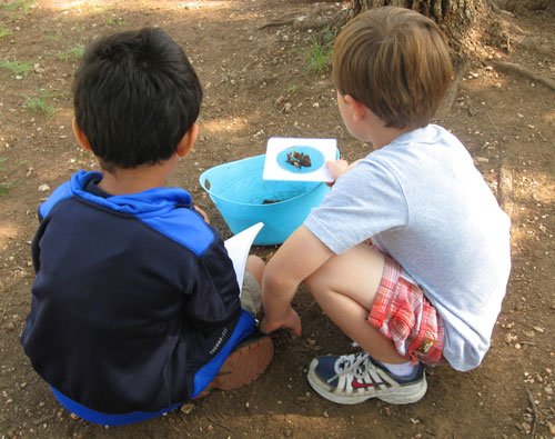 two children studying dirt