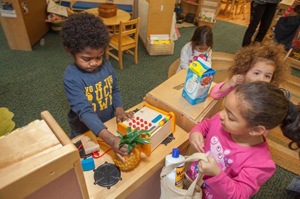 children playing in the house play area of classroom