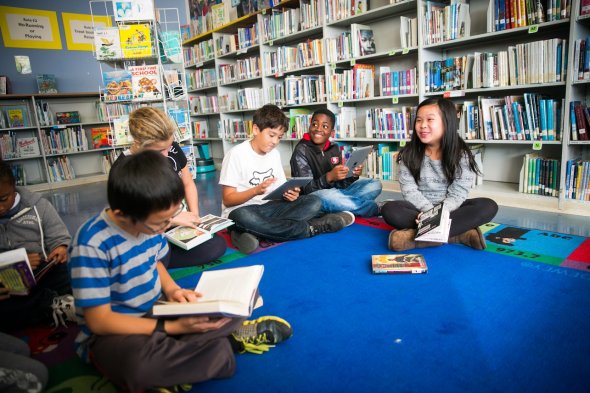 Small group of fifth-grade students reading and socializing in the school library