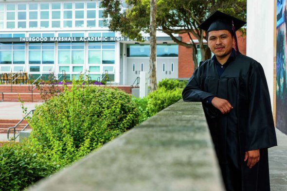 Oliser Aguilar, a Thurgood Marshall Academic High School Class of 2023 graduate, poses in his cap and gown at school