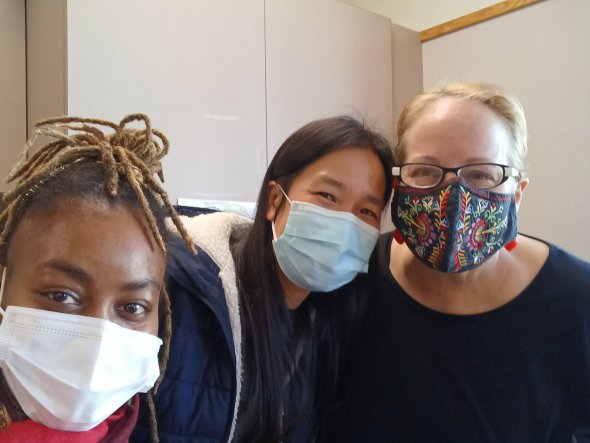three women smiling under masks
