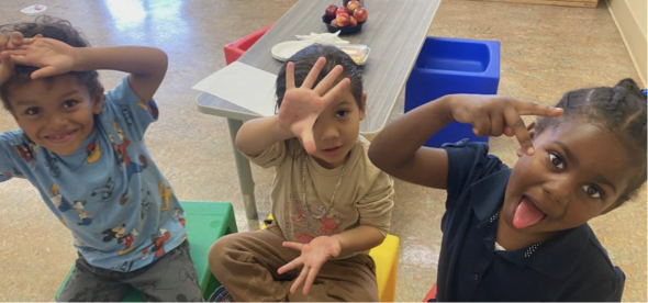 three small children in chairs making silly faces