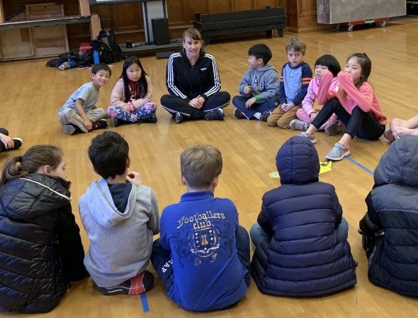 Ms. Rebecca sitting with kids in a circle