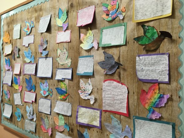 Bulletin board with colorful paper doves and student poems.
