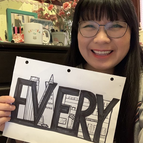 A teacher holds a sign that says "Every"