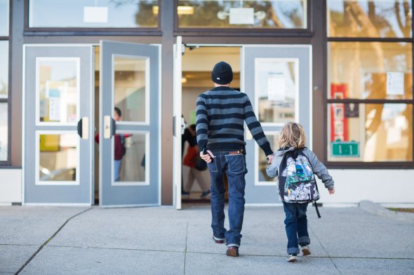 A parent and child walk into a school building together.