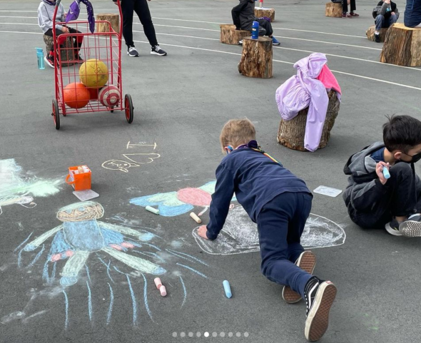 Children drawing with sidewalk chalk in the school yard