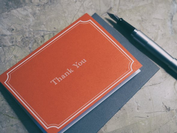 A fountain pen next to red thank you card.