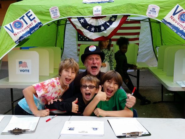 Students and a teacher manage a student voting booth at a school election day event