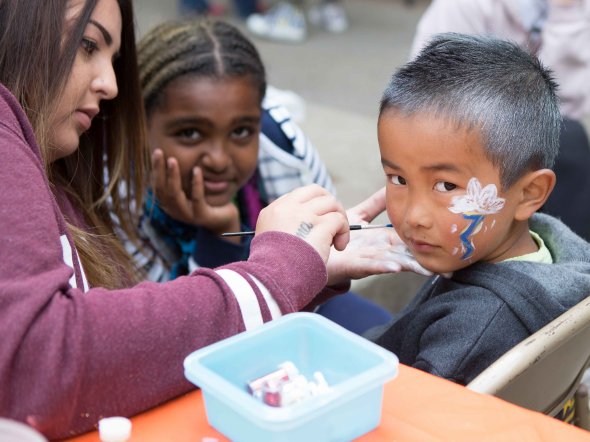 Boy getting his face painted at an outdoor school festival