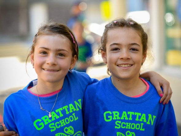 Two girls standing arm in arm at an outdoor school fitness event