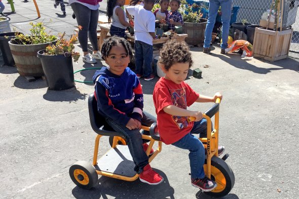 Two boys riding a tricycle
