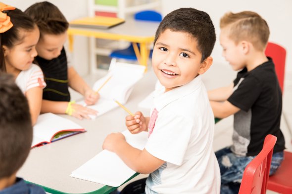 Boy holding pencil and smiling at camera