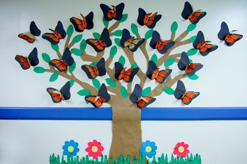 bulletin board of paper butterflies surrounding a tree 