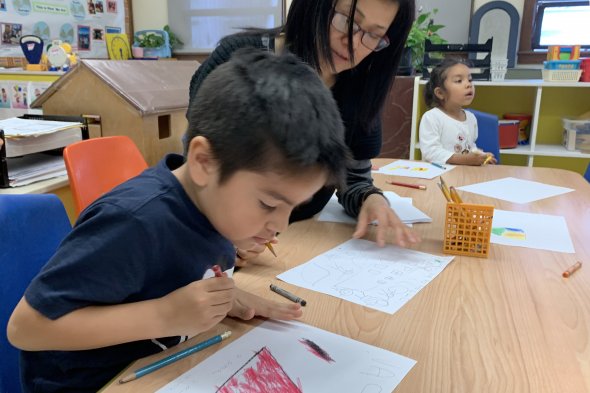 Boy drawing while teacher watches