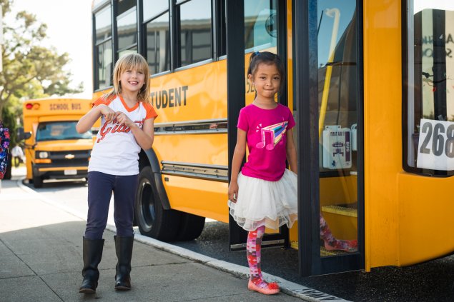 Two elementary school students boarding a yellow school bus