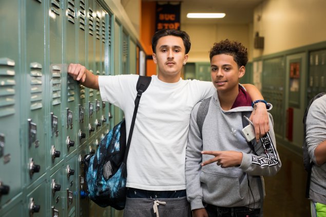 Two high school students standing by lockers