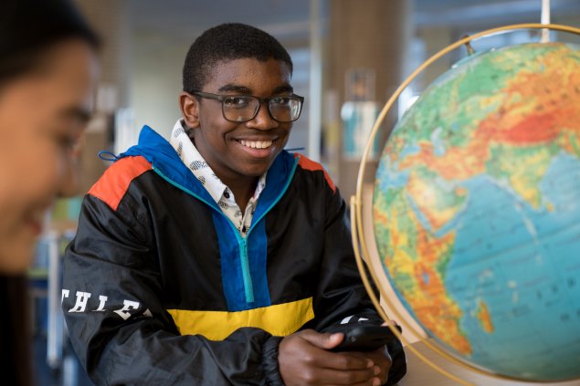 Student smiling with a globe