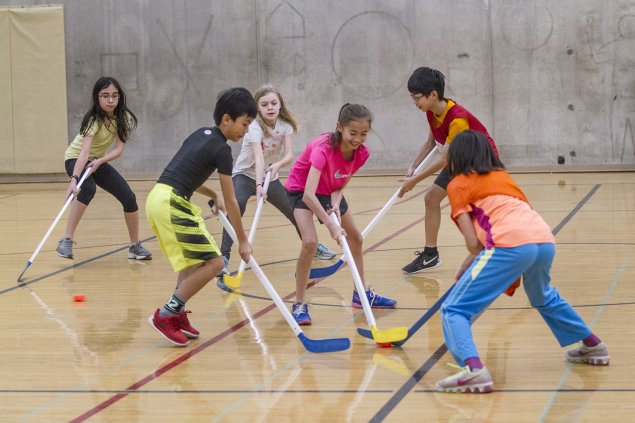 middle school students playing hockey in PE 