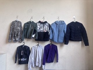 8 jackets hanging on wall from lost and found
