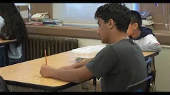 Middle School students writing at a desk - video screenshot