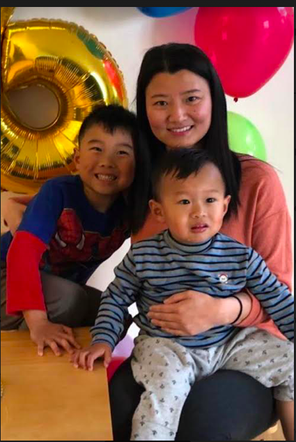 Photograph of Ms. Chen smiling with her two children 